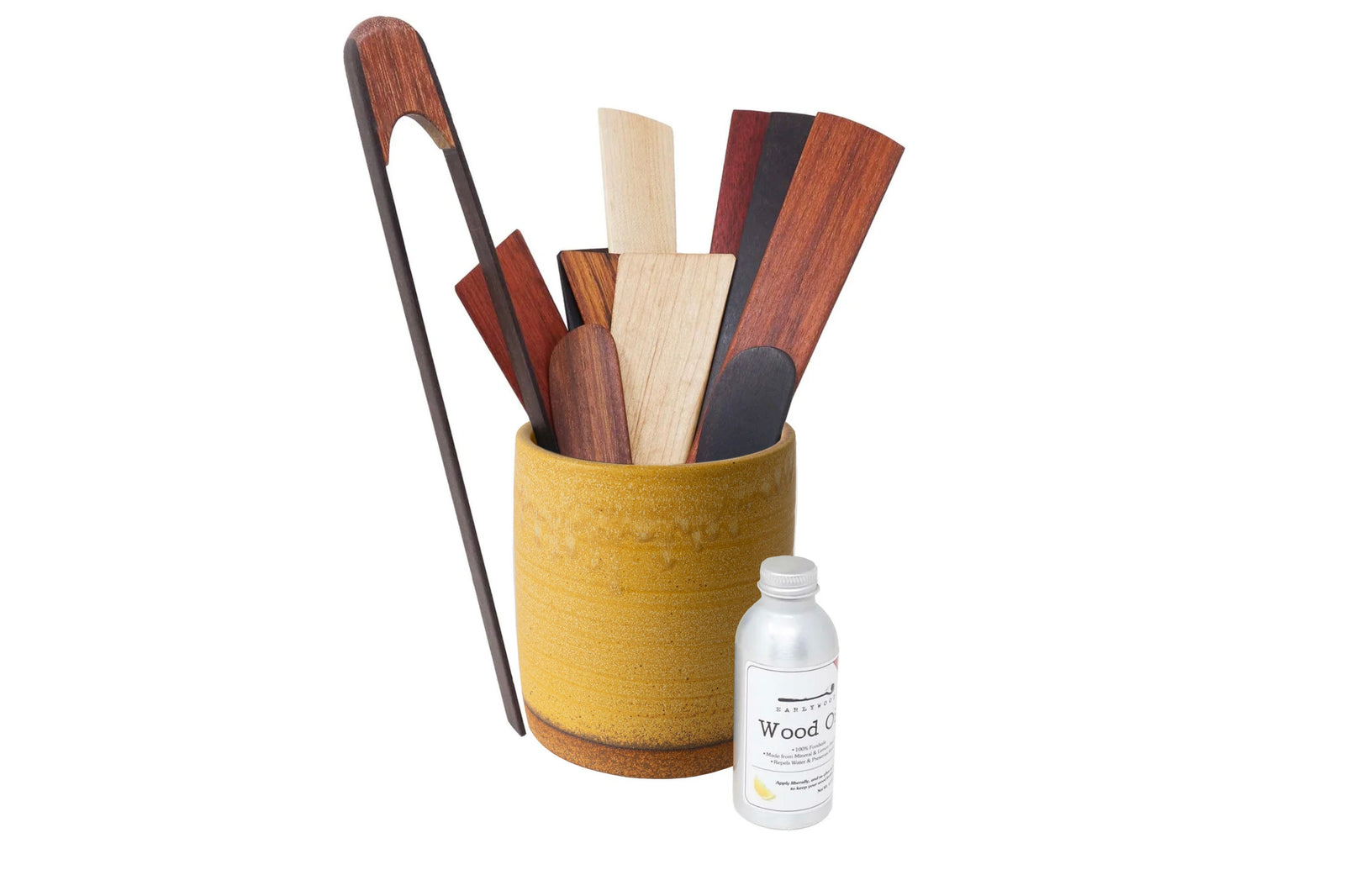 Set of wooden utensils in a teal holder with a bottle of wood care product on a white background